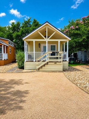 A single-story building with a porch, a staircase, and a small front yard. - Lake Travis Cabin Family Fun Resort Pool & Hot Tub (Austin)