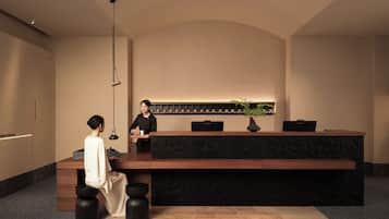 A reception desk with a black marble top, a potted plant, and a wall-mounted display.