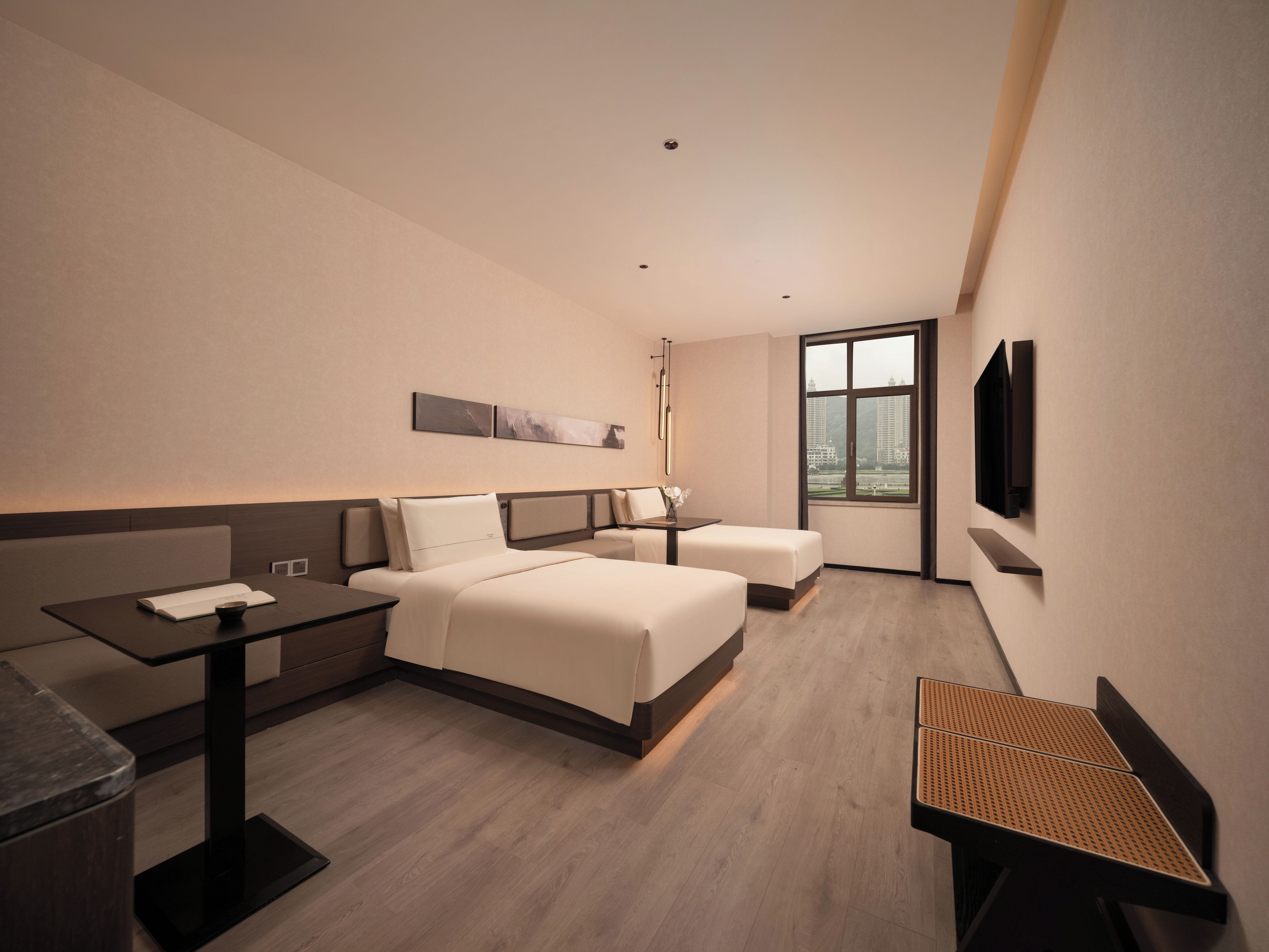 A hotel room with a bed, bedside table, and a TV mounted on the wall.