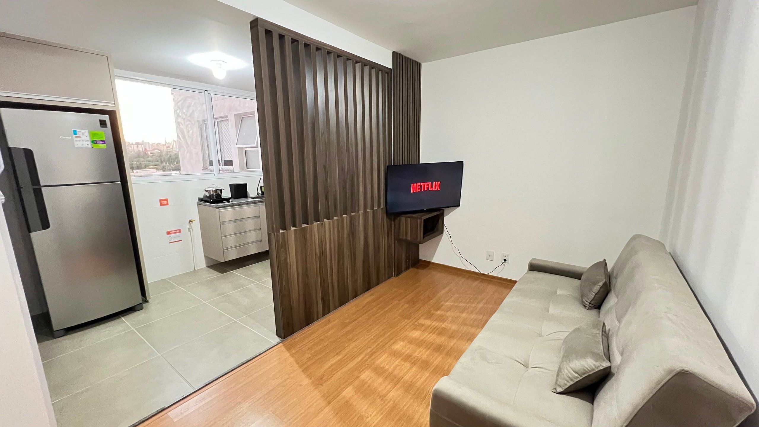 Un espacio de estar moderno con kitchenette, comedor y televisor montado en la pared.
