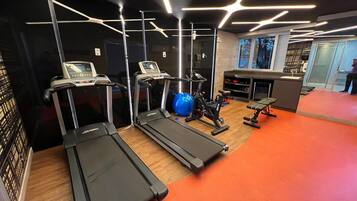 Un gimnasio con cintas de correr, una pelota de ejercicios y equipo de levantamiento de pesas.