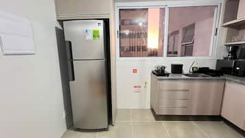 Una cocina compacta con refrigerador, lavamanos y ventana.