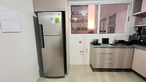 A compact kitchen with a refrigerator, a sink, and a window. - LK Barro Preto 30 (Belo Horizonte)