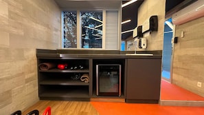 Una cocina compacta con lavavajillas integrado, un refrigerador pequeño y una ventana con persianas.