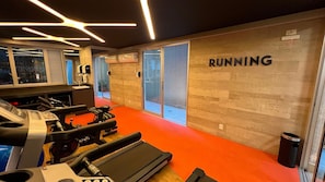 A gym with exercise equipment, a red carpet, and a wall with the word 'RUNNING'. - LK Barro Preto 30 (Belo Horizonte)