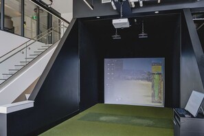 A room with a projector screen displaying a landscape, a laptop on a desk, and a staircase leading to an upper level. - The Oak Haven | 2BR+2BA | Central | Pool&Sauna (Kelowna)