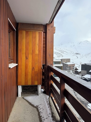 Un balcón de madera con vista a un paisaje montañoso nevado.