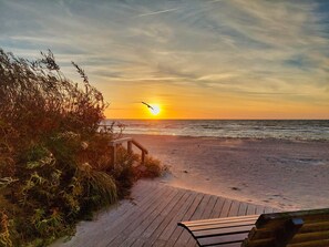 A beach with a wooden walkway leading to a bench. - Seestern 32, a family-friendly vacation rental in Großenbrode. An inviting patio with comfortable patio furniture. Wellness oasis with a sauna and hot tub. Storage space for bicycles & seasonal beach chair included (Großenbrode)