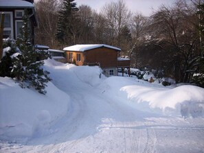 A snow-covered landscape with a wooden cabin and a paved path leading to it. - Holiday Apartment With 2 Bedrooms (Thale)