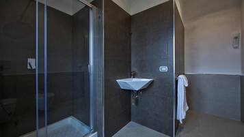 Ein modernes Badezimmer mit einer Duschkabine aus Glas, einem weißen Waschbecken und einem Handtuchhalter.