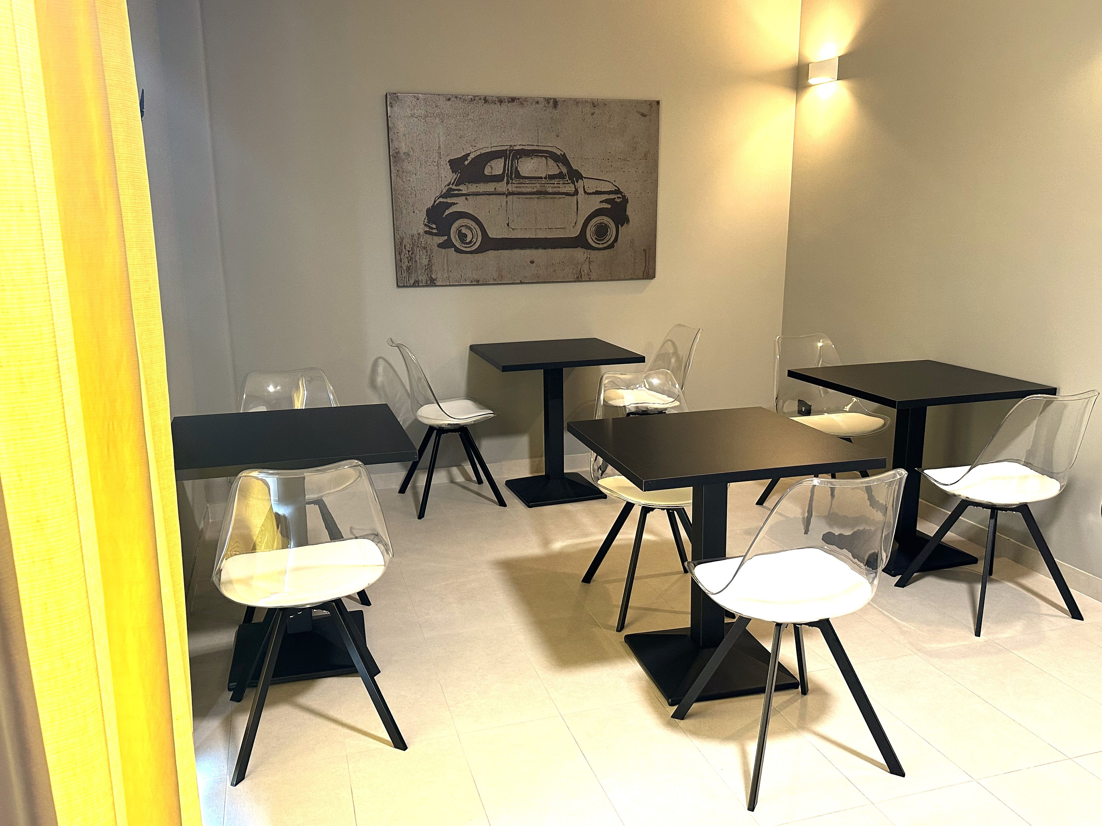Un área de comedor con mesas y sillas, una lámpara de pared e ilustración de un coche.