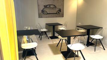 Un área de comedor con mesas y sillas, una lámpara de pared e ilustración de un coche.
