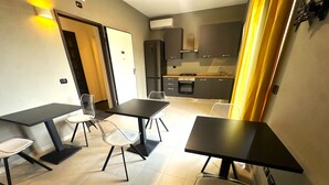 A modern kitchen with a dining area, including a table and chairs, and a separate entrance door. - Lepini Suites Guesthouse (Patrica)