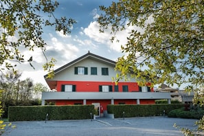 A two-story building with a red and white facade, a flat roof, and a parking area in front.