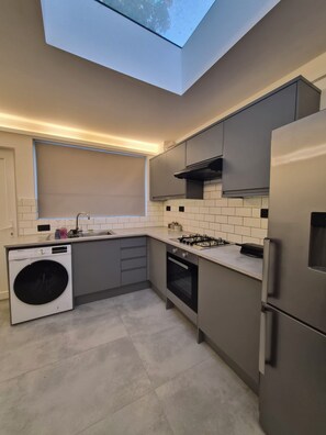 Eine moderne Küche mit eingebauter Waschmaschine, einem Gasherd und einem Edelstahl-Kühlschrank.