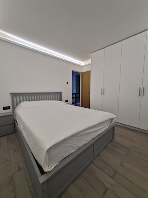 Quarto com cama, guarda-roupa e mesa de cabeceira.