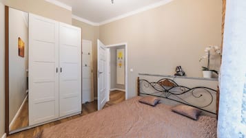 Un dormitorio con una cama, un armario, una puerta y un pequeño estante con una planta.