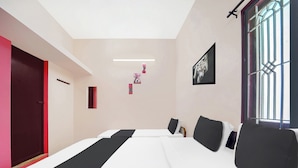 Ett modernt hotellrum med en stor säng, en röd dörr och ett fönster med galler.