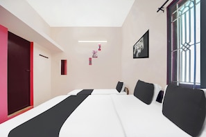 Una habitación de hotel moderna con una cama grande, una puerta roja y una ventana con barrotes.