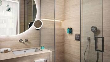 A modern bathroom with a large mirror, a sink, and a shower.