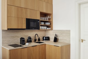 Cozinha moderna com armários de madeira, micro-ondas preto, máquina de café, torradeira e porta-facas.