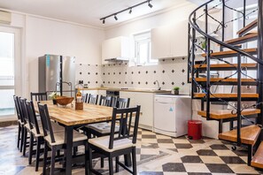 A kitchen with a wooden dining table, black chairs, a refrigerator, a dishwasher, and a spiral staircase. - Stone house in the very center with pool table, two balconies and the sea view (Bol)