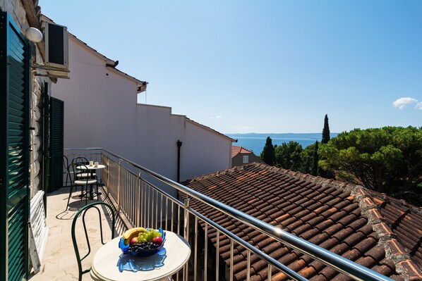 A balcony with a table and chairs, a bowl of fruit, and a view of the sea. - Stone house in the very center with pool table, two balconies and the sea view (Bol)