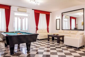 Una habitació amb taula de billar, dos sofàs, una taula de cafè i un mirall gran.