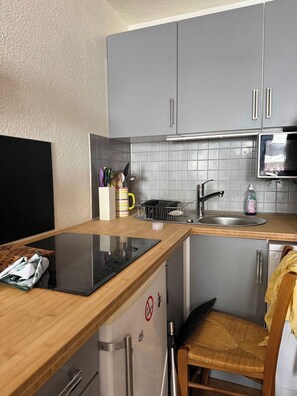 A compact kitchen with grey cabinets, a stainless steel sink, and a microwave. - "V24" by Versant Collection (Les Belleville)