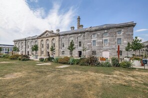 A historic building with a symmetrical facade, large windows, and a central chimney. - Luxury 2bed Apartment in historic RoyalWilliamYard (Plymouth)