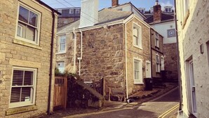 A narrow street with stone buildings, a visible staircase, and a clear sky. - Dean Cottage - A Beautiful C17 Fisherman's Cottage (St Ives)