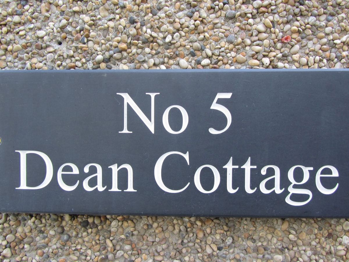 A black sign with white lettering that reads 'No 5 Dean Cottage.'