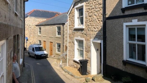 A narrow street with stone buildings, a parked car, and a clear sky. - Dean Cottage - A Beautiful C17 Fisherman's Cottage (St Ives)