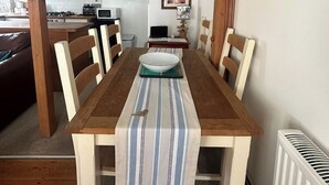 A dining area with a wooden table, chairs, and a striped table runner. - Dean Cottage - A Beautiful C17 Fisherman's Cottage (St Ives)