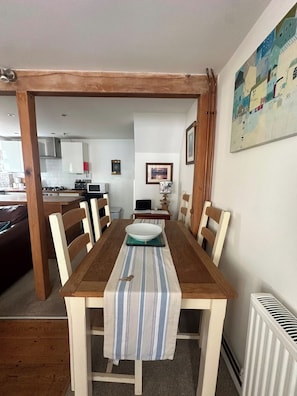 Un comedor con una mesa de madera, sillas y un camino de mesa a rayas.