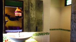 A bathroom with a white sink, green and white patterned tiles, and a hanging lamp. - soi one boutique bedrooms (pai)