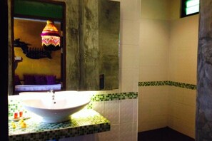 A bathroom with a white sink, green and white patterned tiles, and a hanging lamp. - soi one boutique bedrooms (pai)