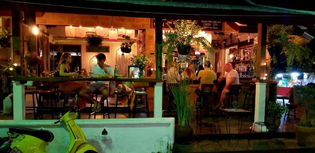 An outdoor seating area with tables and chairs, a bar area with stools, and a scooter parked in the foreground.