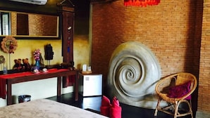 A room with a large bed, a round decorative wall piece, a wicker chair, and a hanging light fixture. - soi one boutique bedrooms (pai)