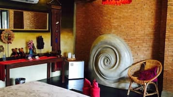 Ein Zimmer mit einem großen Bett, einem runden Wandkunstwerk, einem Korbstuhl und einer Hängeleuchte.