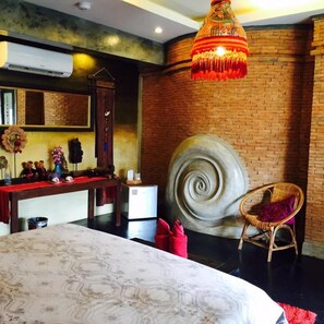 A room with a large bed, a round decorative wall piece, a wicker chair, and a hanging light fixture. - soi one boutique bedrooms (pai)