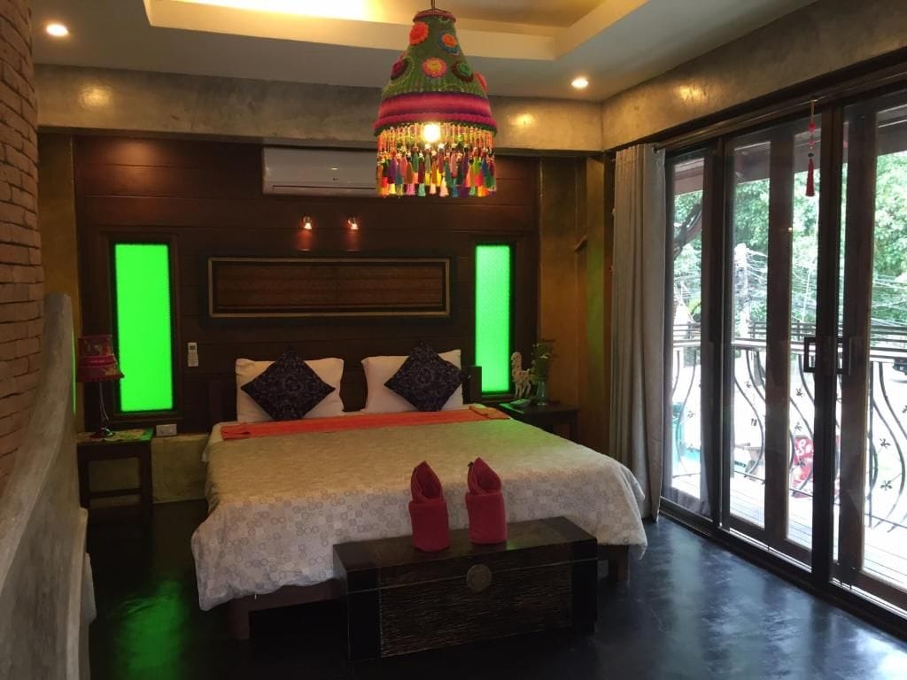 A bedroom with a large bed, a decorative hanging light, and a view through a glass door.