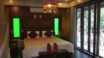 A bedroom with a large bed, a decorative hanging light, and a view through a glass door.