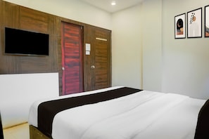 A bedroom with a bed, a TV mounted on the wall, and a wardrobe with a red door. - Hotel O Laxman Nagar Baner (Pune)