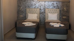 A hotel room with two beds, a marble-patterned wall, a modern pendant light, and an air conditioning unit. - Labyrinth Hotel (Georgioupoli, Crete)