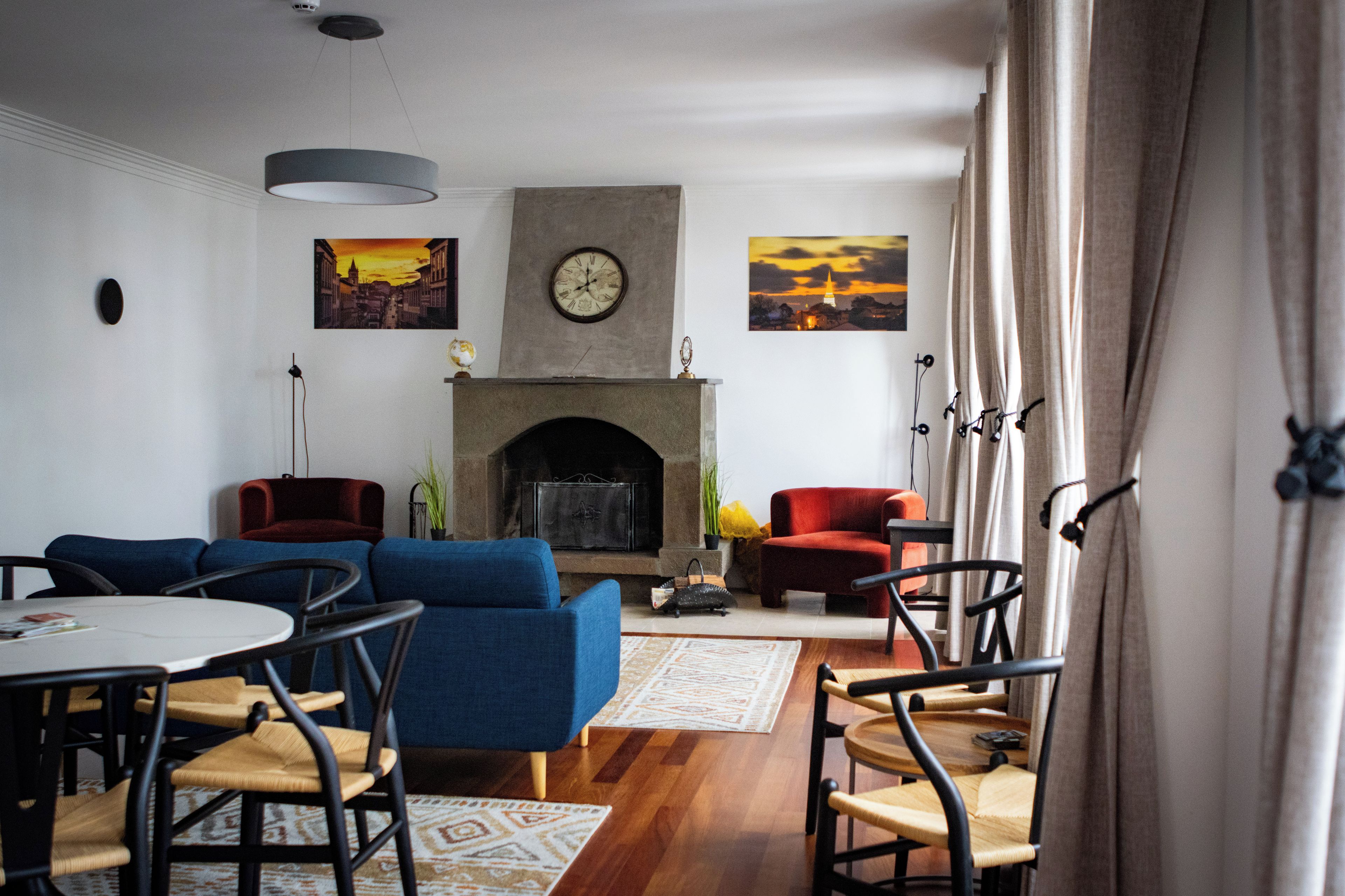 A living room with a fireplace, blue sofas, and a dining area with chairs and a table.