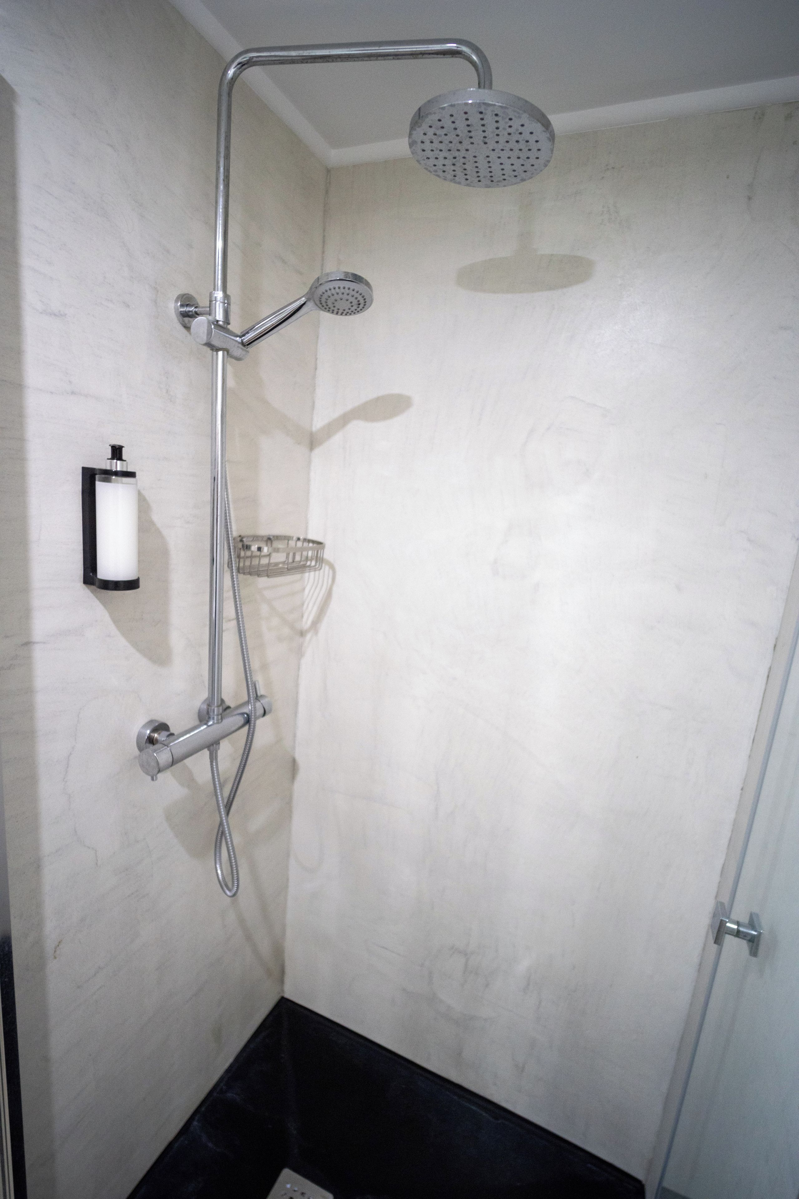 A shower with a handheld showerhead and a wall-mounted faucet.