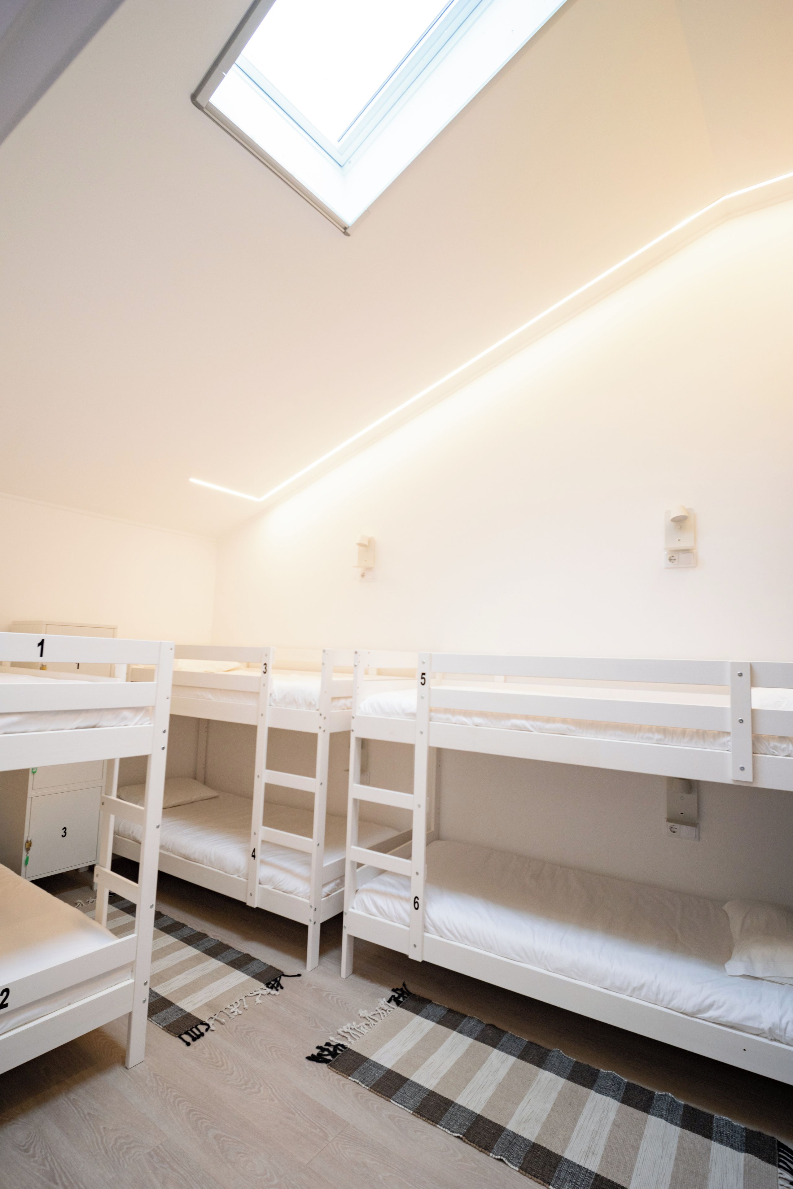 Un dormitorio con literas, un tragaluz y una alfombra a cuadros.