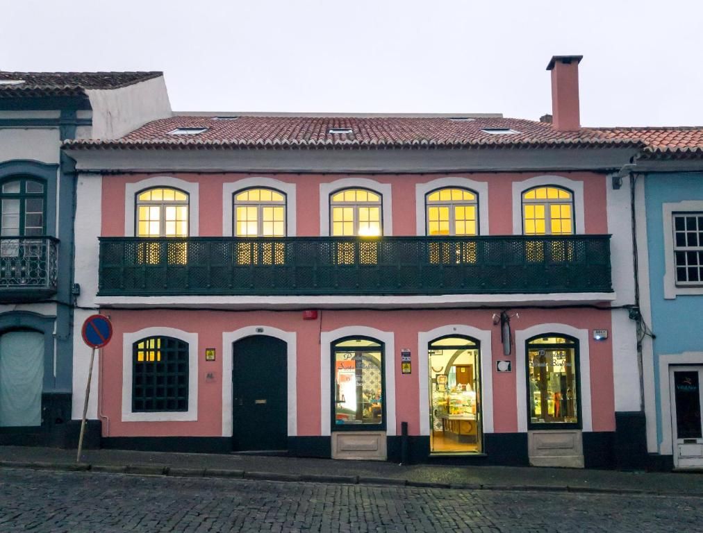 A two-story building with a balcony, a shop on the ground floor, and a street sign.