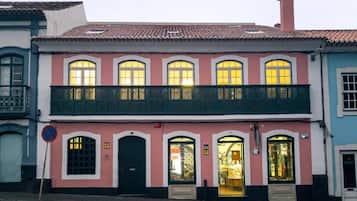 A two-story building with a balcony, a shop on the ground floor, and a street sign.